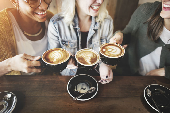3 female friends smiling toasting coffee on hand