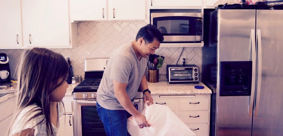 Dad doing household chores while daughter observes
