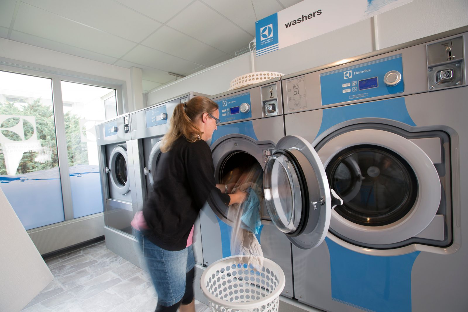 Woman taking her clothes out of machine in laundromat
