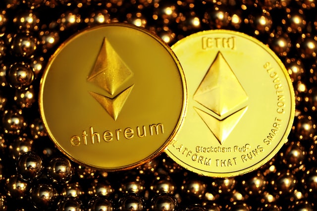 Two Ethereum coins, one showing its front side and the other its back side, on top of metal balls