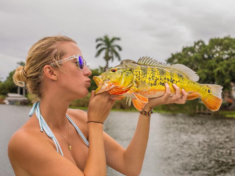 Vicky Stark holding a big yellow fish and posting as if to kiss it