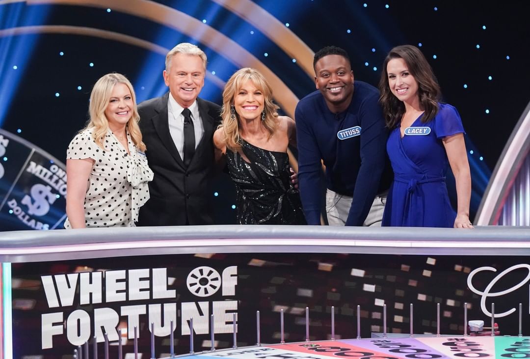 Pat Sajak and Vanna White pose with three Wheel of Fortune contestants
