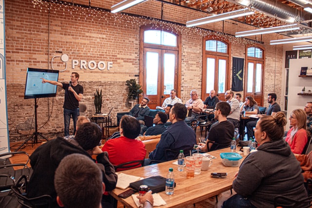 Man in black T-shirt and jeans explains PowerPoint presentation in a FinTech start-up office