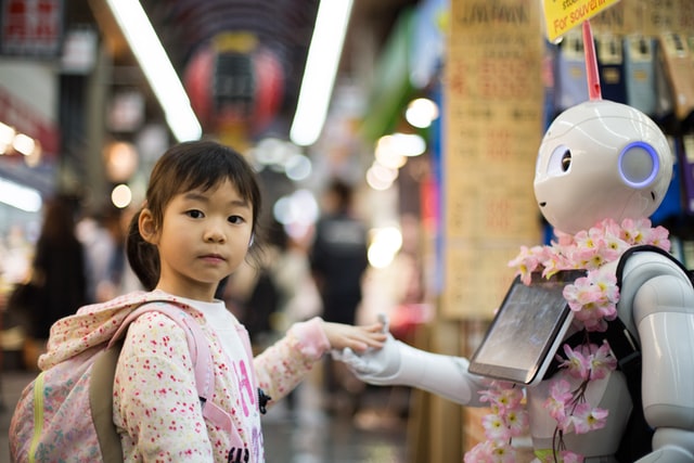 Little Japanese girl touches the hand of a robot at Kuromon Market in Osaka