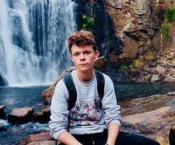 Harry holland sitting in front of a waterfall wearing a backpack