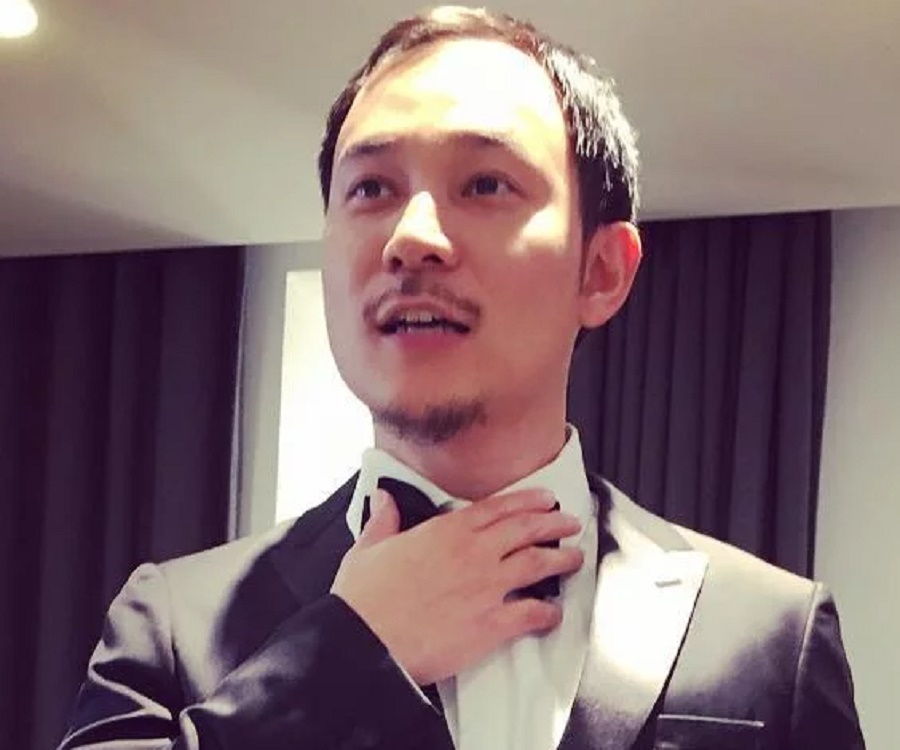Justin Hakuta wearing a three-piece suit and holding his bow tie