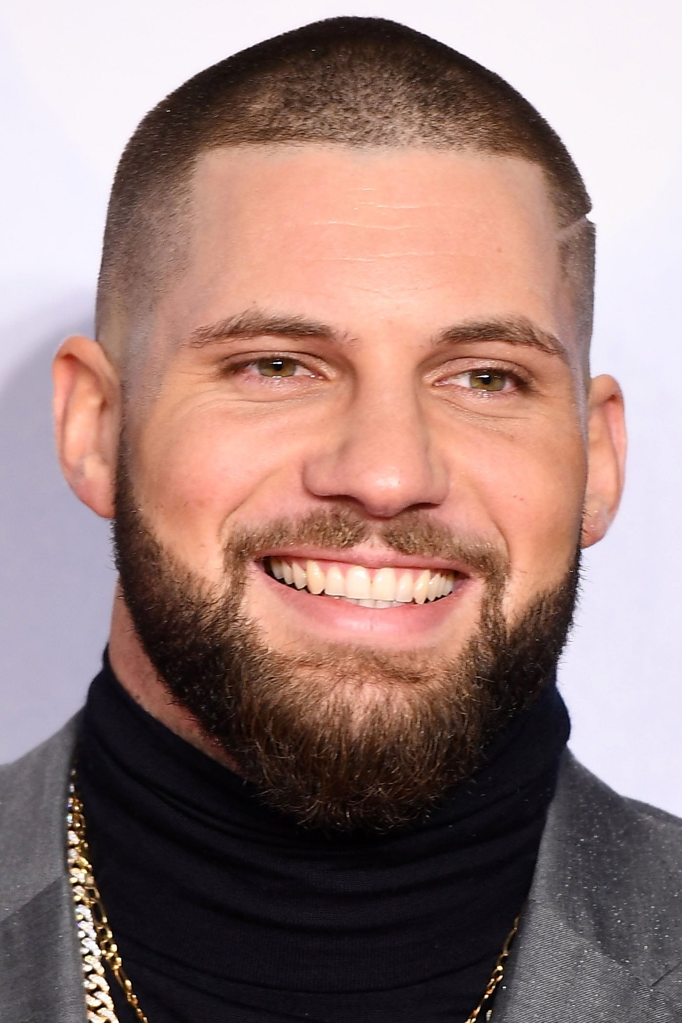 Florian Munteanu headshot wearing a black turtleneck and gold chain necklace 