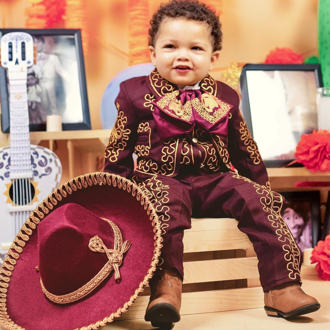 Gekyume Onfroy in maroon mariachi attire with sombrero and brown boots at his Coco-themed second birthday party