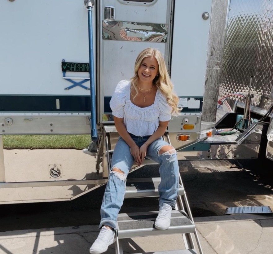 Jenna Boyd sitting on steps of trailer while working on set