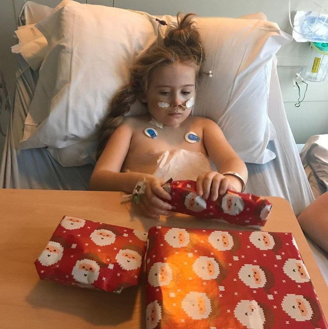 Female child with cancer unwraps Christmas present in her hospital bed