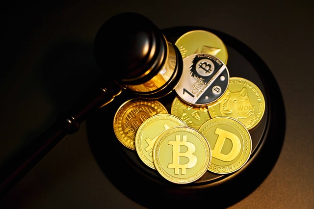 Gavel and Bitcoin, Dogecoin, and Ethereum placed on a circular wooden pad