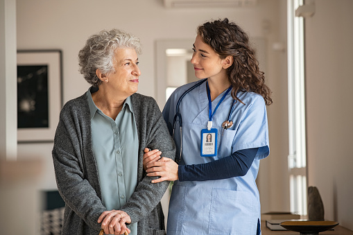 A nurse happily takes care of her old woman patient