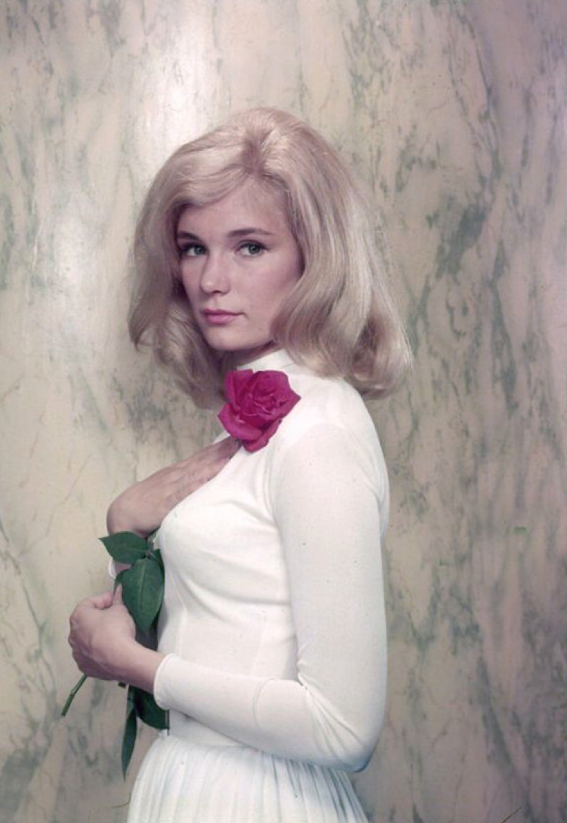 Yvette Mimieux wearing a white long sleeve dress while holding a red rose close to her heart