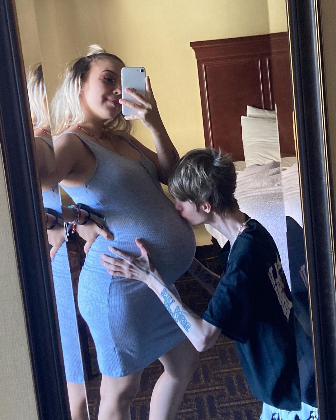 Daddy Long Neck kisses the tummy of pregnant girlfriend while she takes a mirror selfie