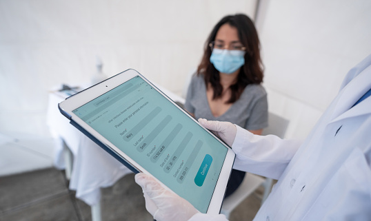 A doctor holding an iPad and a patient wearing a blue face mask
