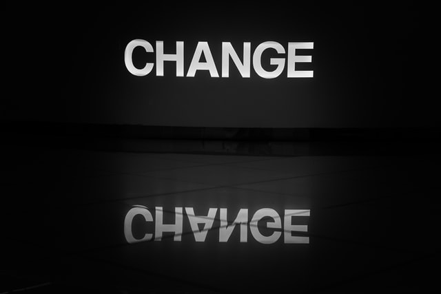 Word ‘change’ in capital letters illuminated in white and reflected on a tiled floor