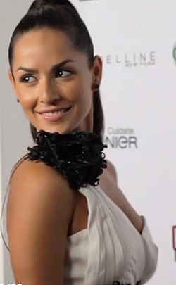 Carmen Villalobos wearing a white gown and her hair in a high ponytail during a brand party