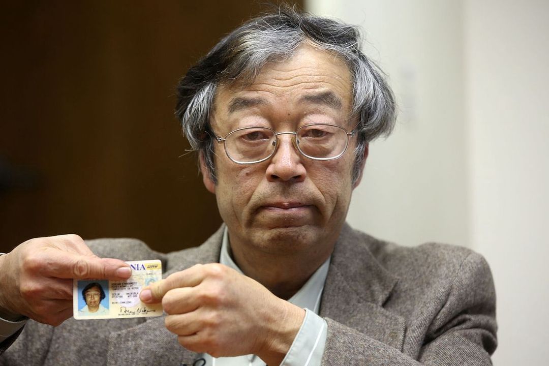Satoshi Nakamoto holding his I.D. while covering some parts with his forefingers