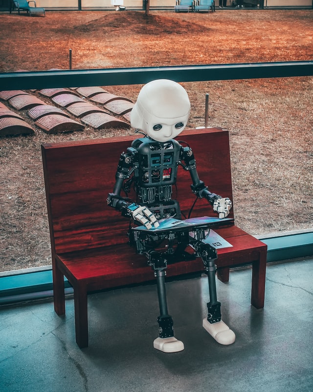 A black and white robot kid in Seoul sitting on a bench reading