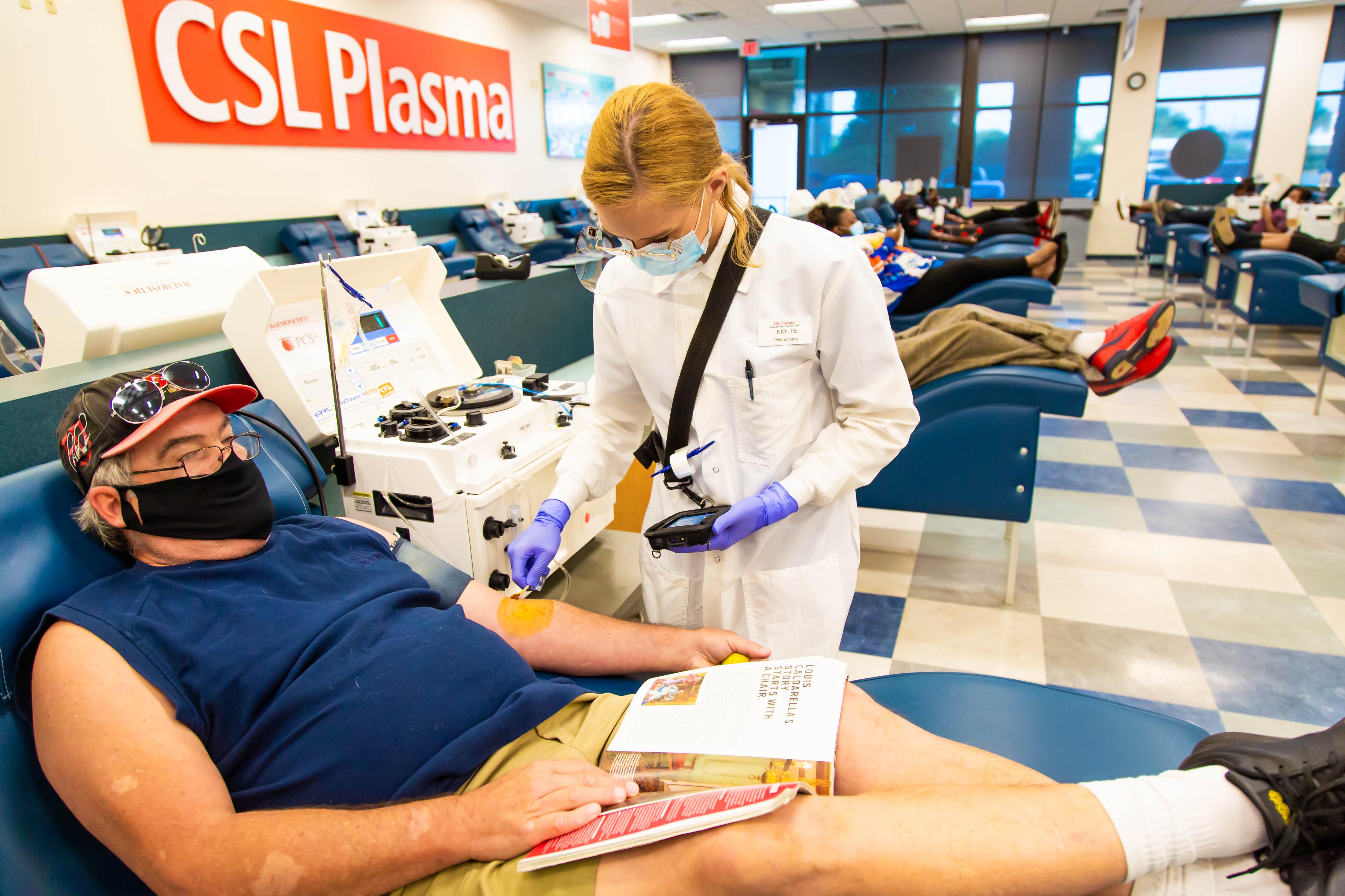 Female CSL Plasma personnel attends to a male middle-aged plasma donor