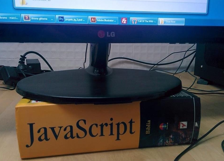 LG desktop monitor placed on top of a thick JavaScript book