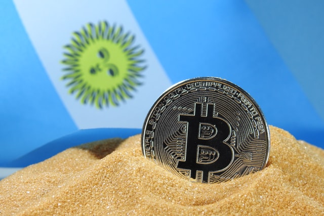 A silver Bitcoin cryptocurrency with Argentina flag in the background