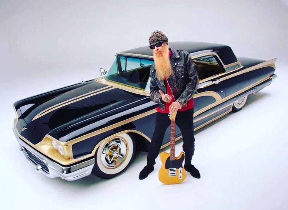 Billy Gibbons holds an electric guitar and shows off his mint Ford Thunderbird