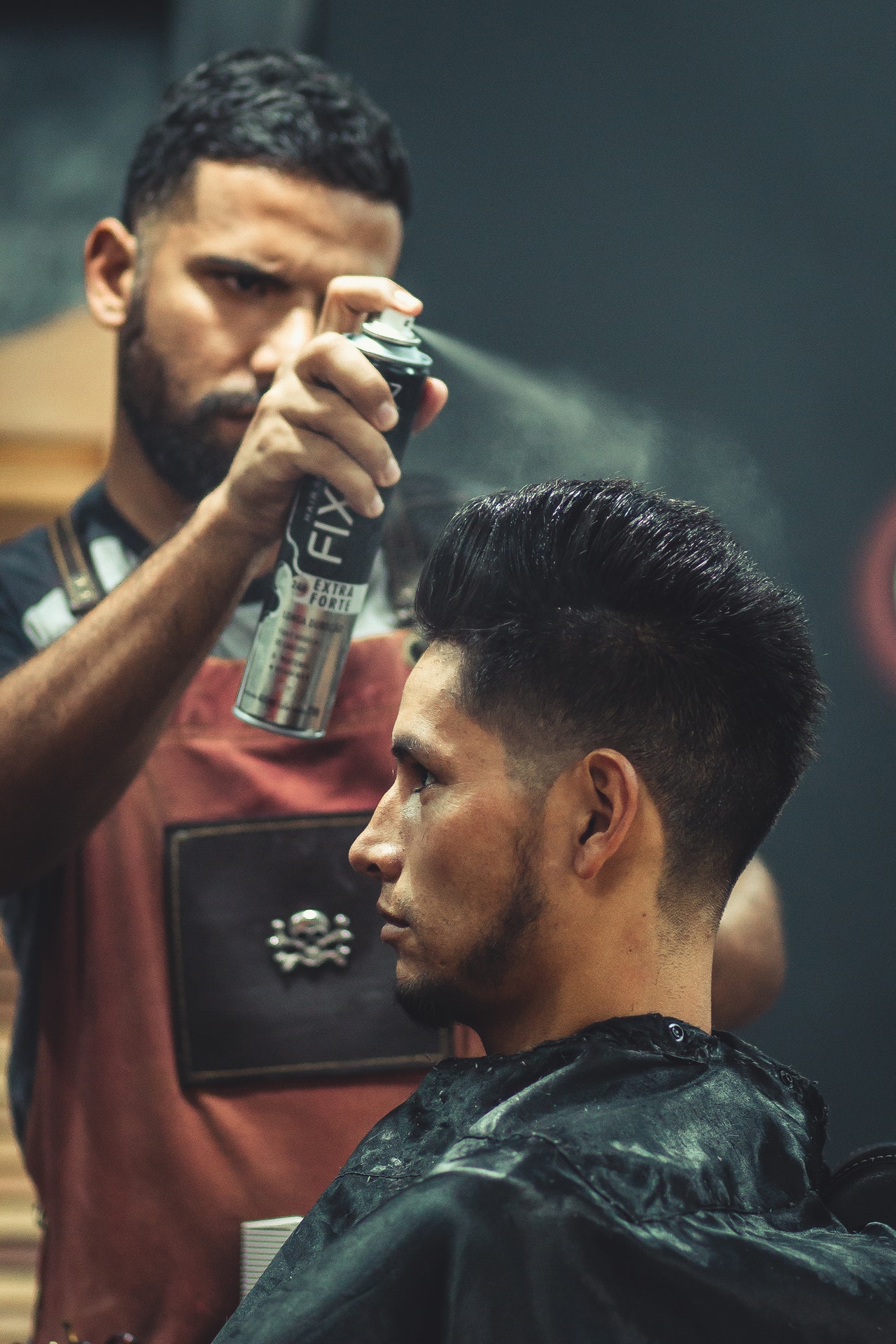 Male hairstylist uses hair spray on a male client