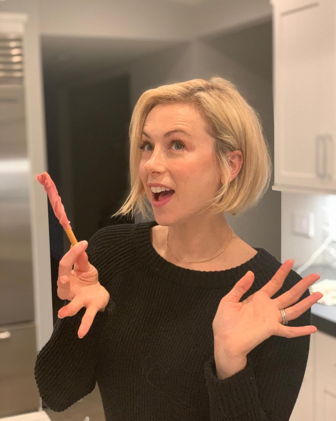Iliza Shlesinger holds a breadstick wrapped in prosciutto or uncooked, dry-cured ham