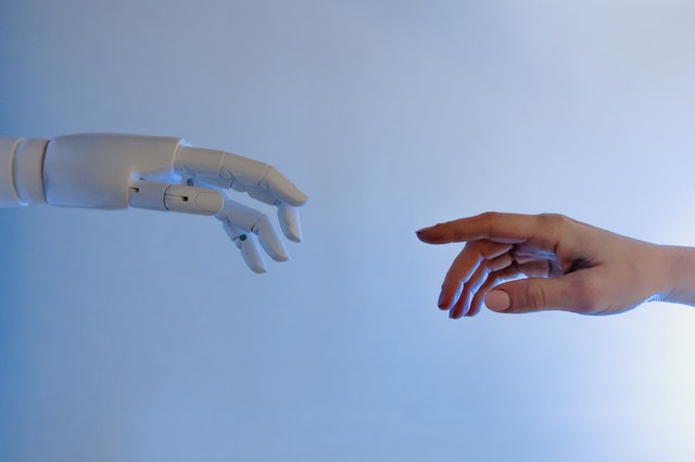 Hand of a robot and a human hand reaching out to each other
