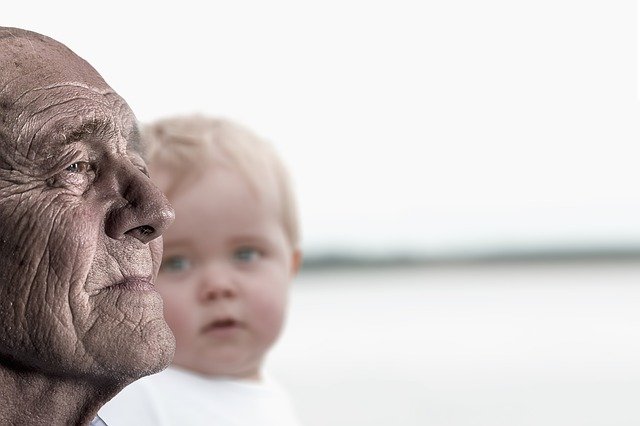 Sideview of a bald old man, with a young child in the background
