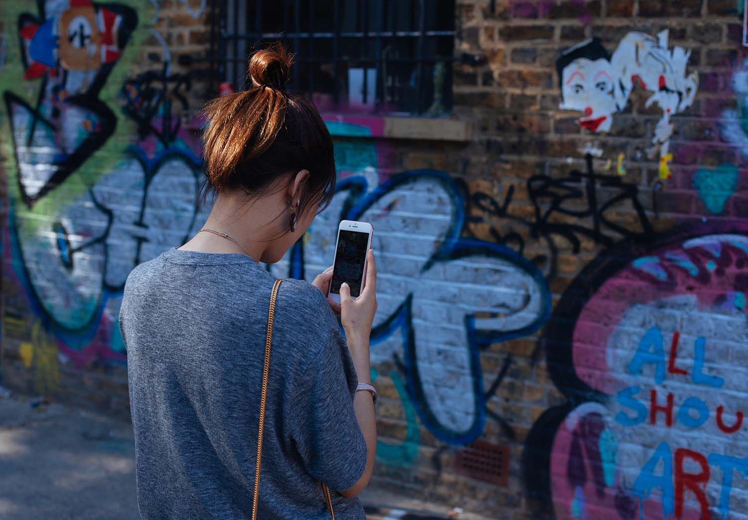 A girl with a bun taking a picture of a design on a wall