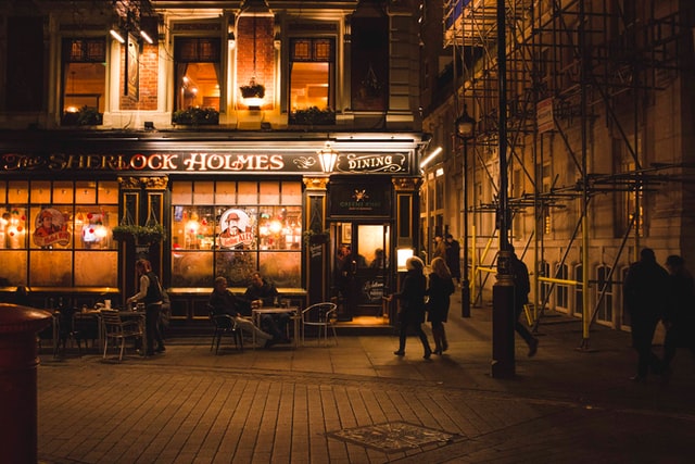 People dining and walking outside Sherlock Holmes Public House & Restaurant at night in London