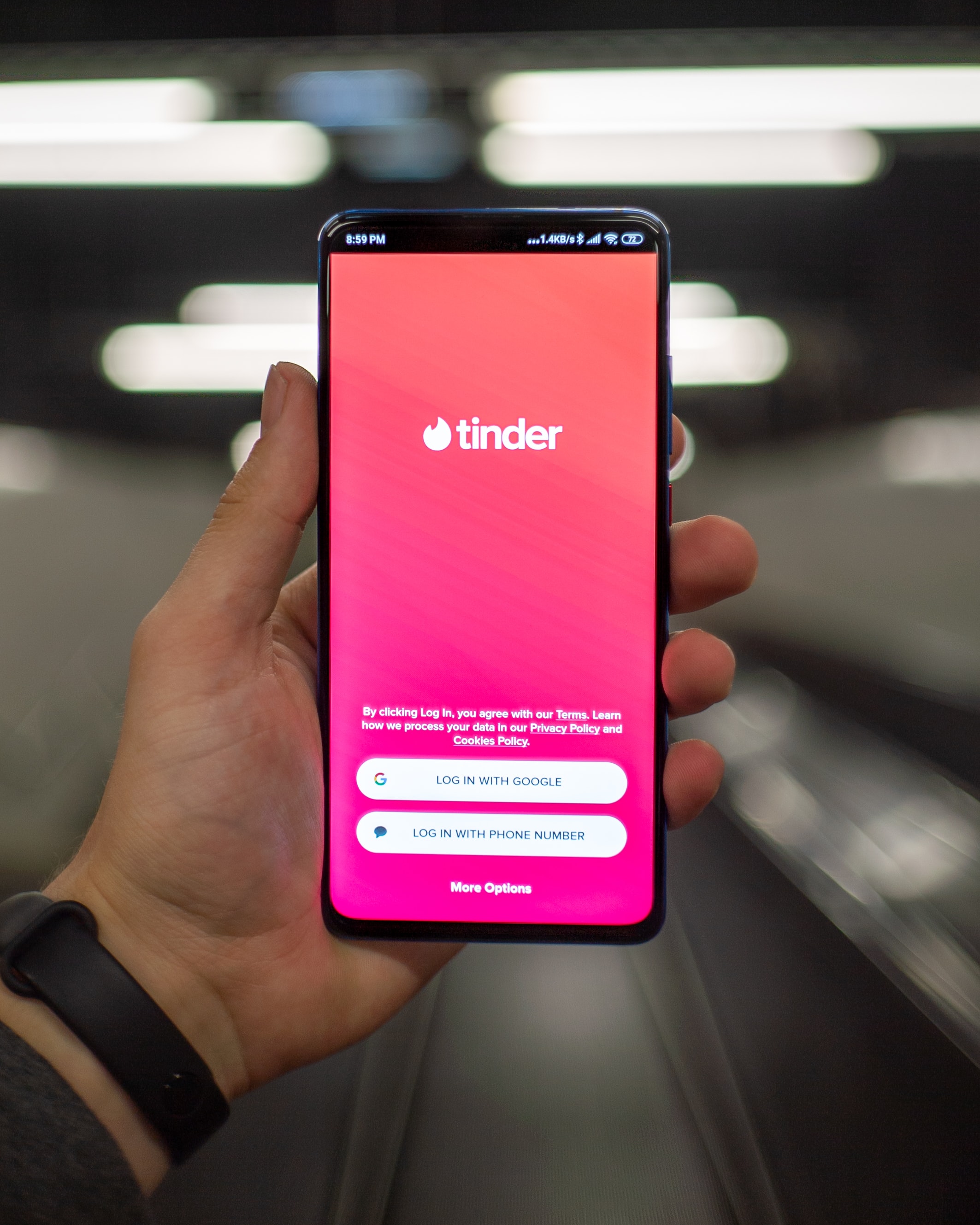 A hand holding a phone with tinder log in on screen