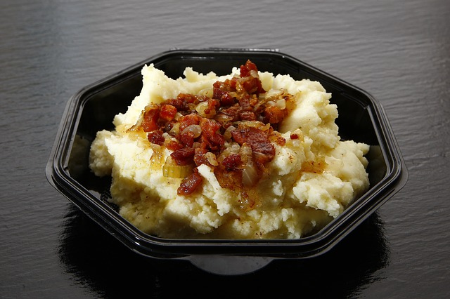Instant mashed potatoes in a black octagonal container topped with bacon and garlic bits