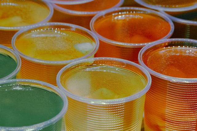 Green, yellow and orange Jell-O in transparent plastic cups