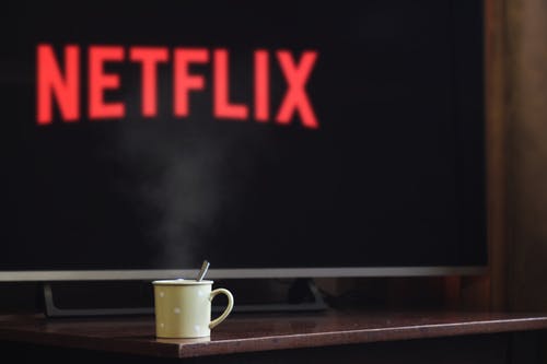 Netflix logo shown up in the television and a cup of hot drink on the table with a spoon in it
