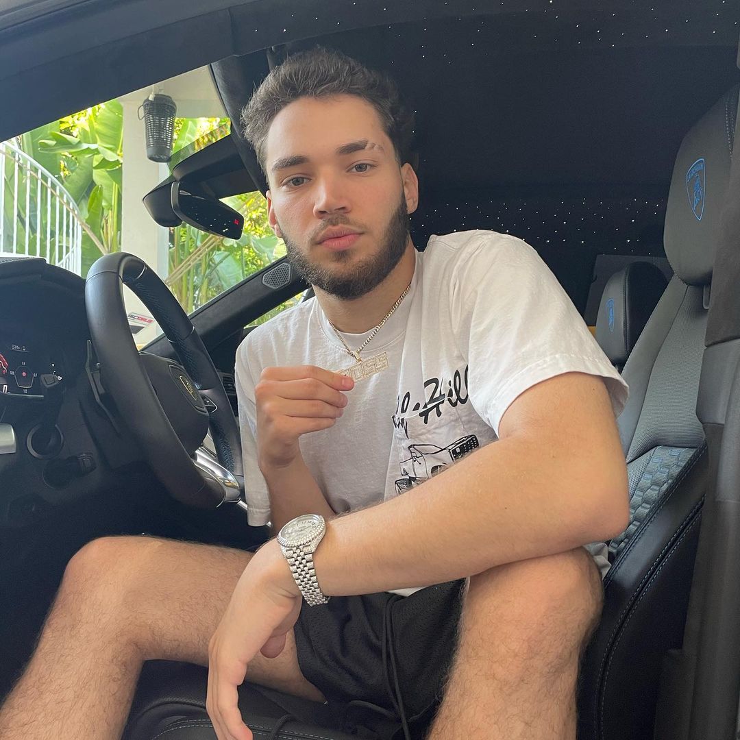Adin ross in white shirt posing while setting a car