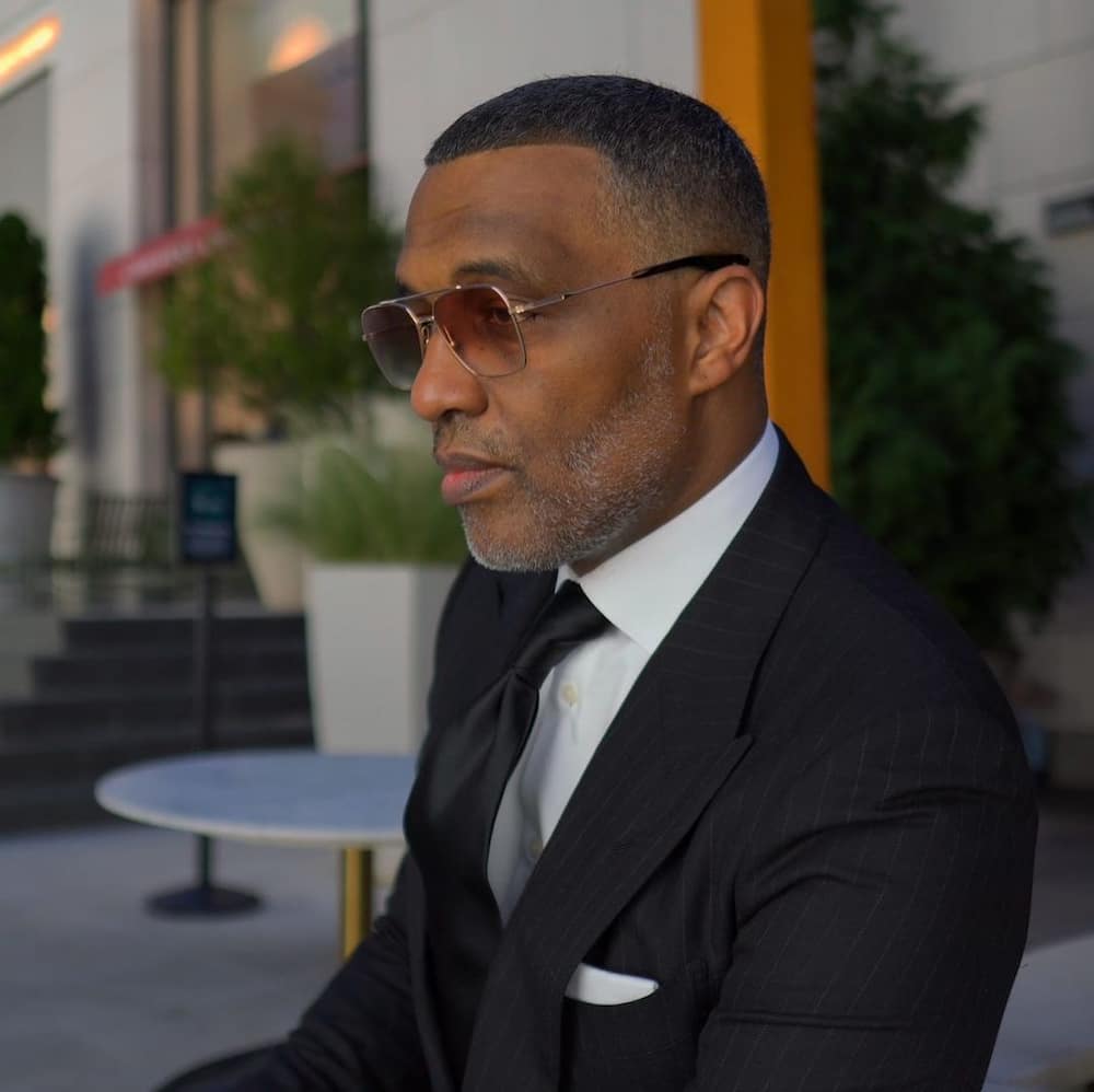 Kevin samuels side pose wearing sunglasses and black three-piece suit
