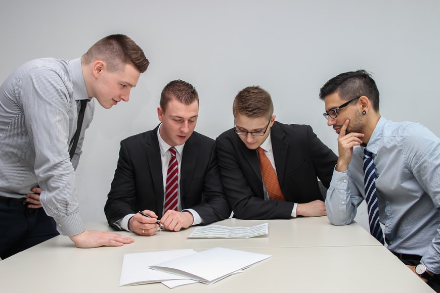 Four people in suits looking at documents together