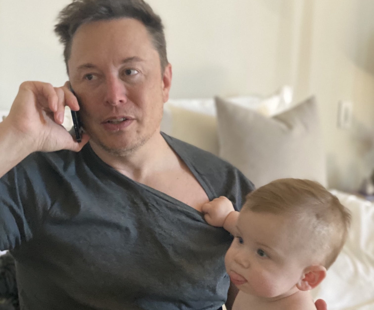 Elon musk talking on the phone while carrying a baby