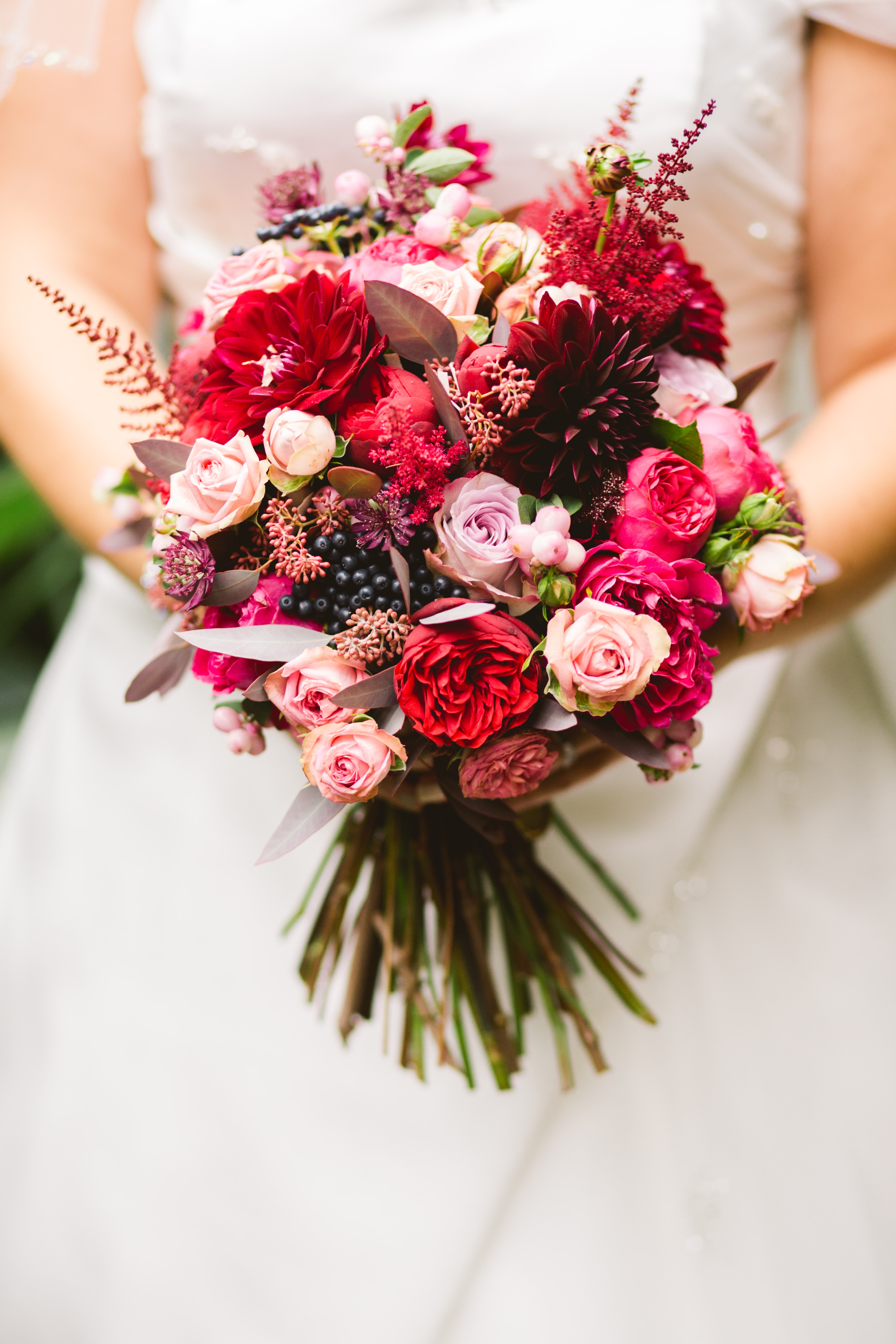 Bride holding a flower bouquet of red and pink flowers