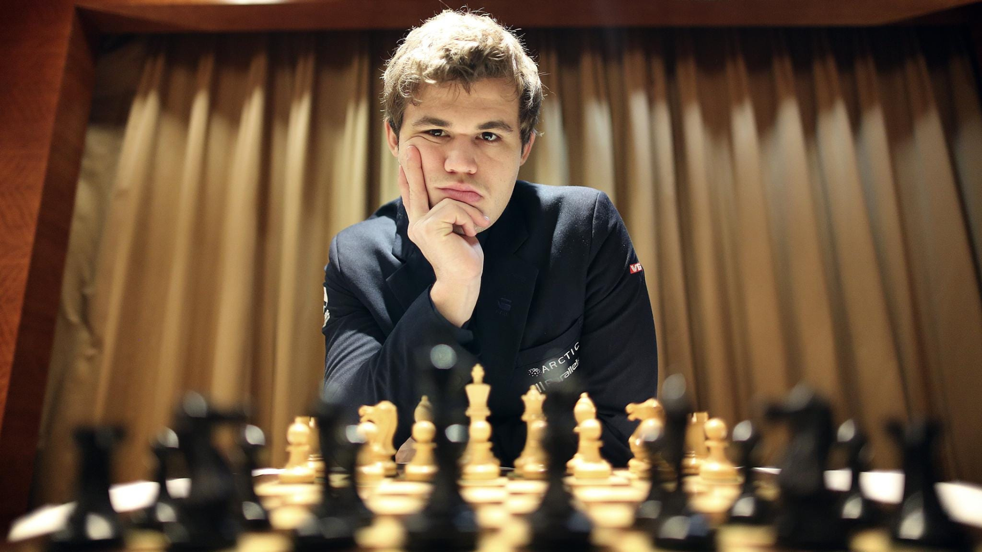 Magnus carlsen playing chess with his hand on his face