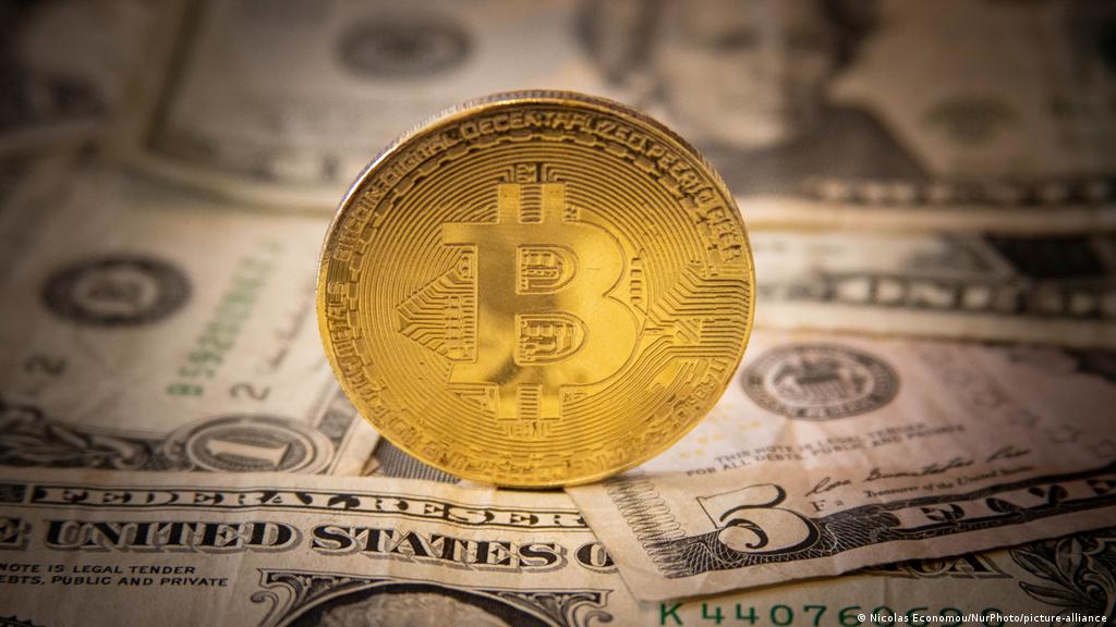 Gold bitcoin token with dollars beneath it