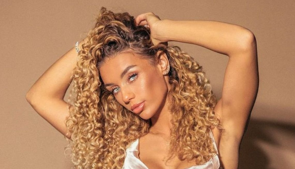 Jene Frumes wearing silky top and holding her curly hair up