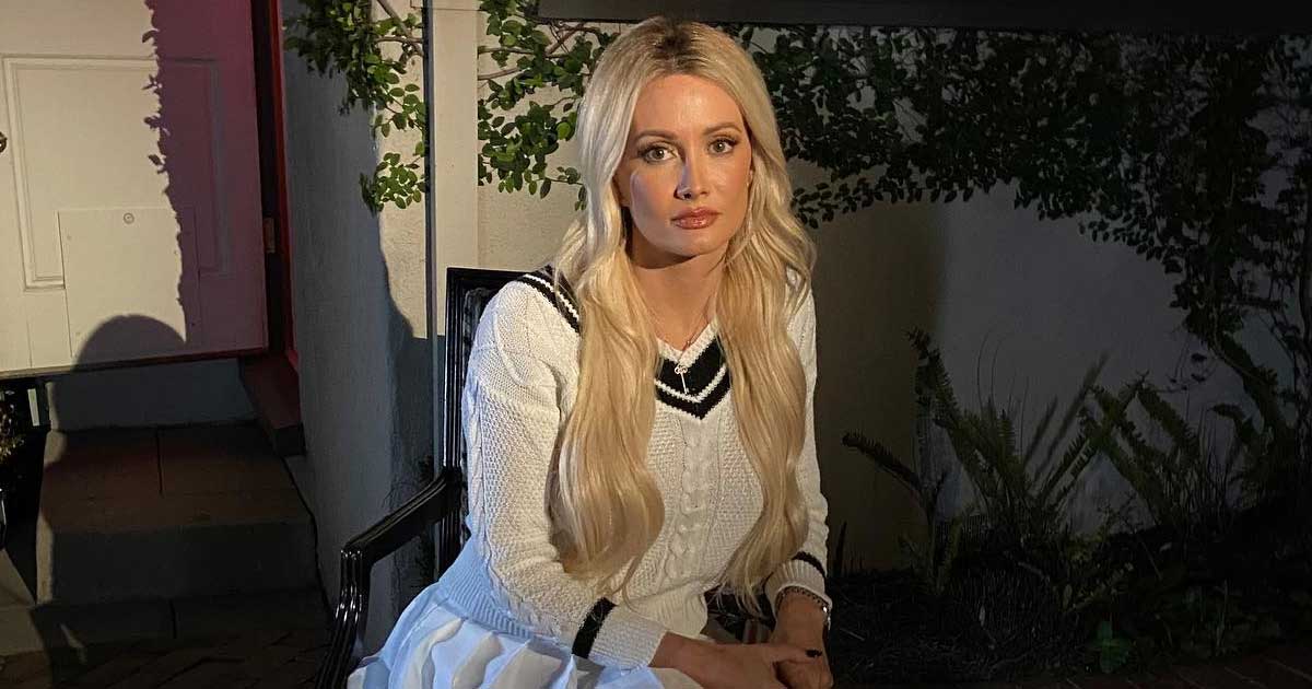 Holly Madison wearing a cardigan and white skirt