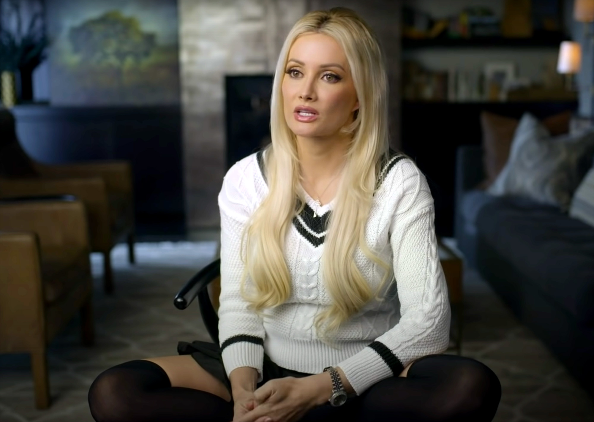 Holly Madison sitting in a chair and wearing white cardigan
