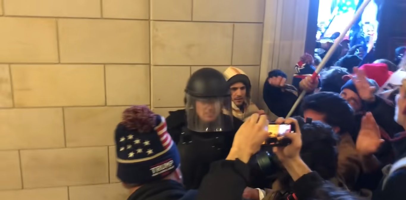 Protesters at the U.S. Capitol confronts a police enforcer wearing face shield and helmet