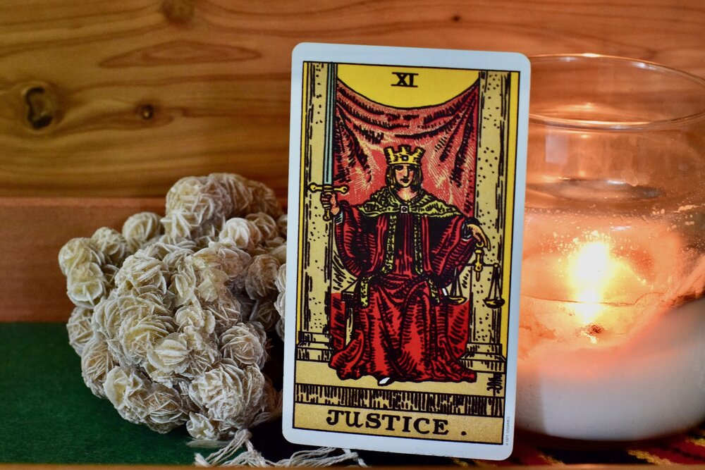 Justice Tarot Card with plants and candle behind it