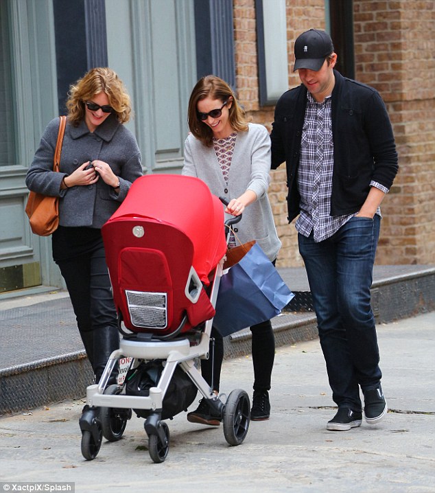 Emily Blunt, John Krasinski, and a relative is looking down at baby Hazel in the stroller while walking down the street